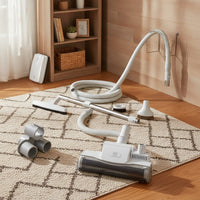 a central vacuum turbo carpet beater kit: air-driven TK280 nozzle, hose, telescopic wand, floor brush, upholstery tool, dusting brush, crevice tool, tool caddy and wall hose hanger shown in a cozy den with a textured area rug and warm wood floors