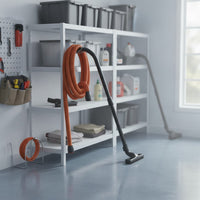 a garage central vacuum attachment kit: hose, floor brush, telescopic wand, upholstery tool, dusting brush, crevice tool and wall hose hanger shown in a clean home garage with epoxy-coated concrete floors and storage shelves